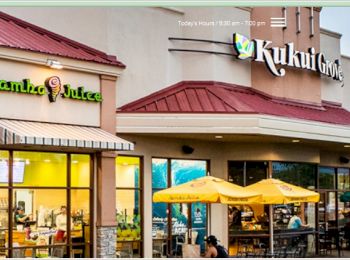 The image shows a Jamba Juice and Kukui Grove shopping center with outdoor seating under yellow umbrellas, illuminated by soft daylight.