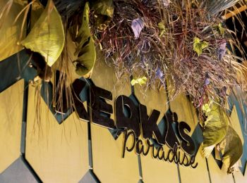 A decorative wall with plants and a sign that reads "KEOKI'S paradise" in stylized text. The design includes geometric patterns and foliage.